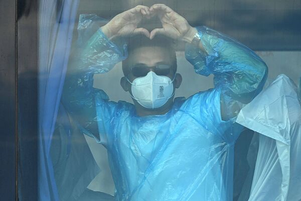 Un pasajero del Hondius hace la forma de un corazón desde uno de los autobuses que trasladó al pasaje a los aviones en Tenerife.