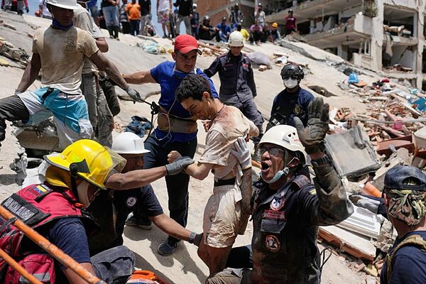 Los equipos de rescate sacan con vida a un hombre de entre los escombros.